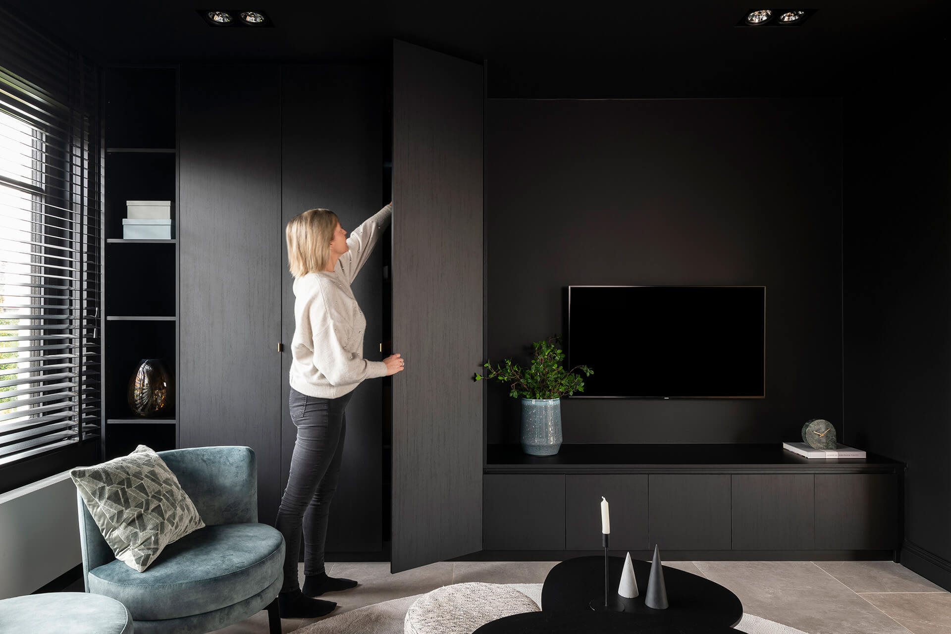 A tall storage cupboard combined with a low TV unit. Colour: Elegant Black. Handles on TV unit: finger pull handle.