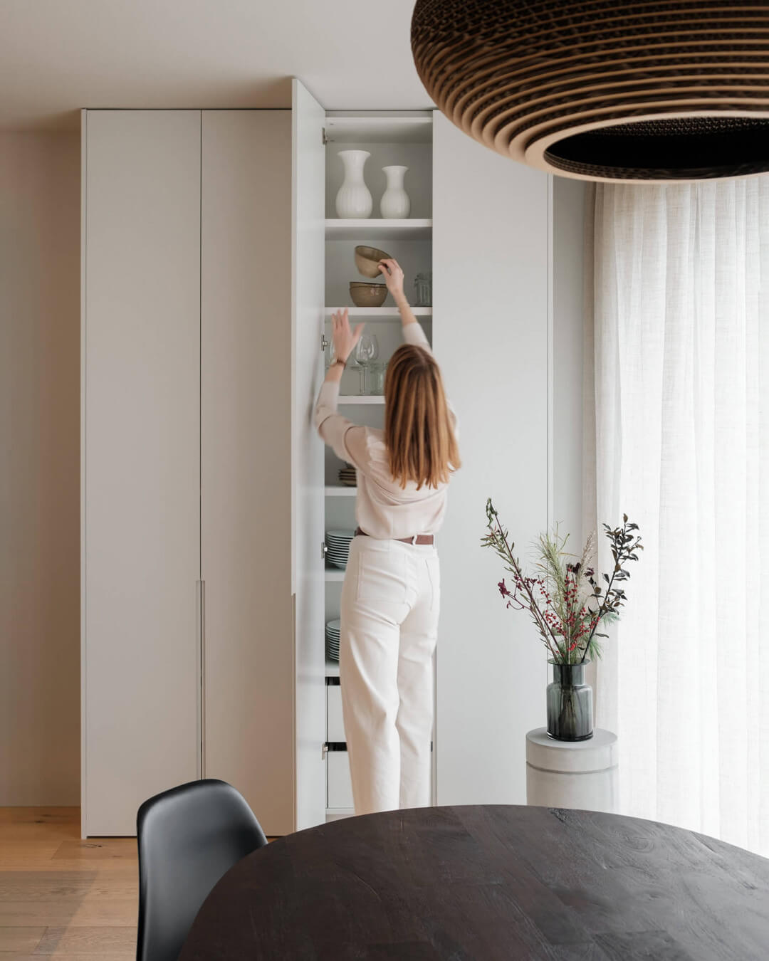 Servieskast op maat in de woonkamer, met lange ingefreesde handgrepen in de kastdeuren