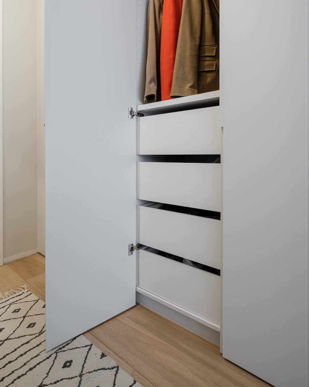 Open custom-made cloakroom cabinet with MDF cabinet doors and long milled handles