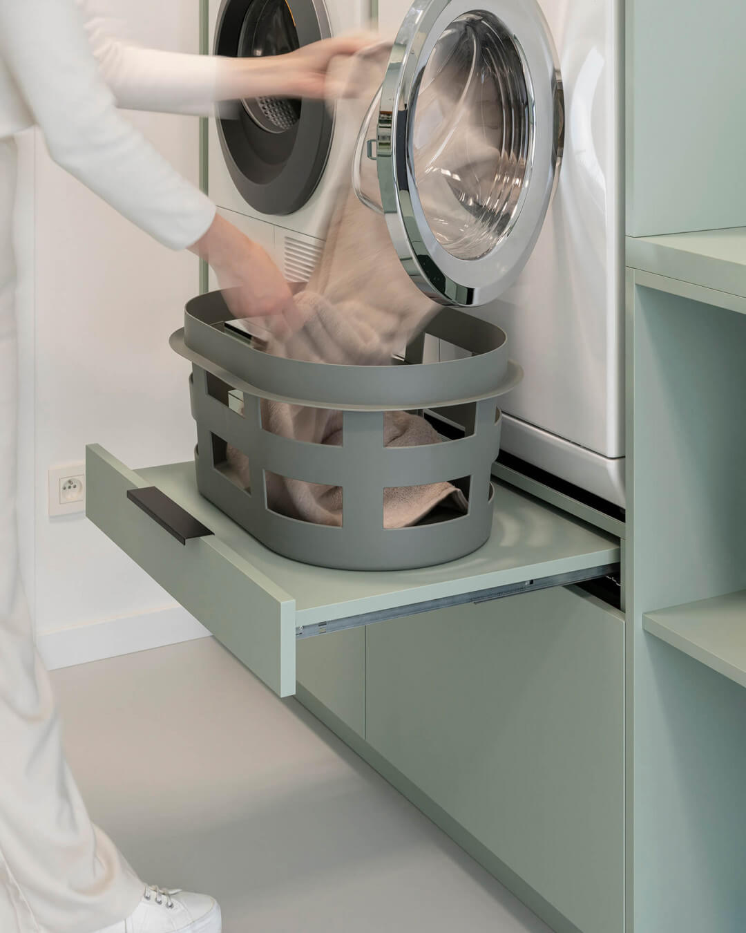 Pull-out shelf for the laundry basket in a custom laundry cabinet in the color Industrial Green