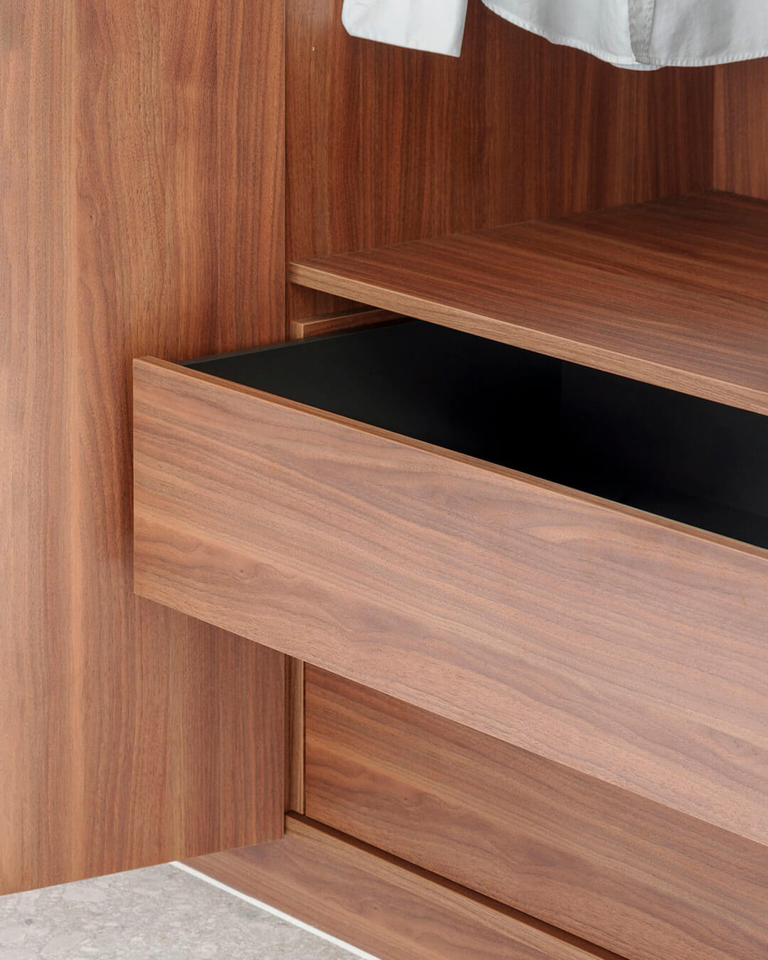 Detail of a self-closing Ta'Or Box drawer, with black interior and drawer front in Lorenzo Walnut wood shade.