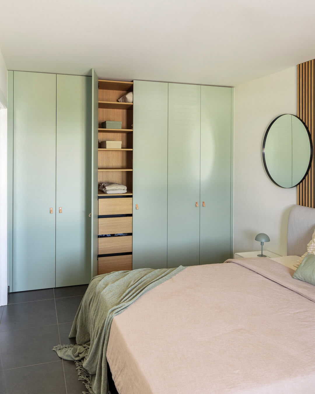 Bedroom with soft green tones and warm wood shades by Maatkasten Online