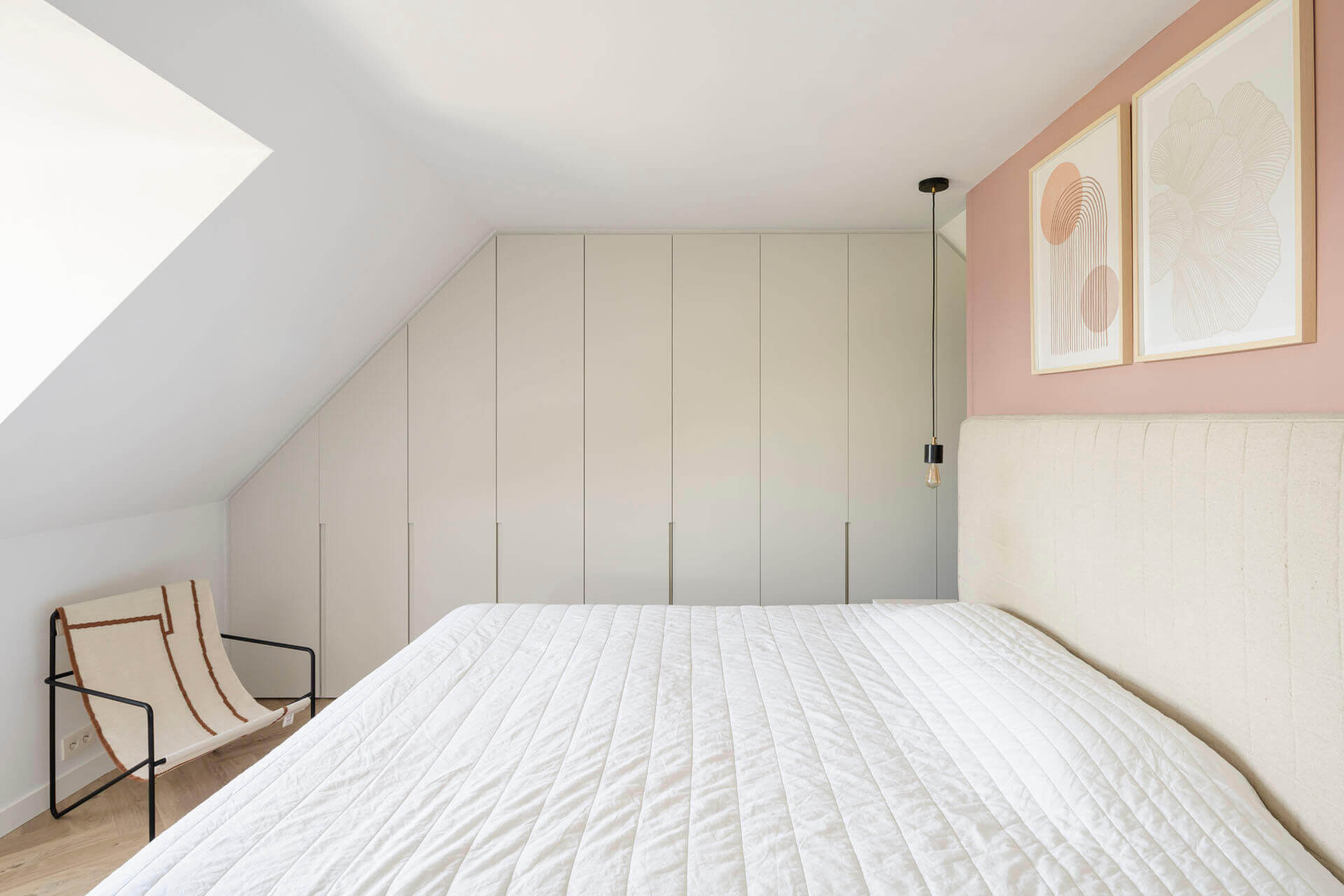 Custom-made wardrobe with long milled handles, in the bedroom under a slanted roof.