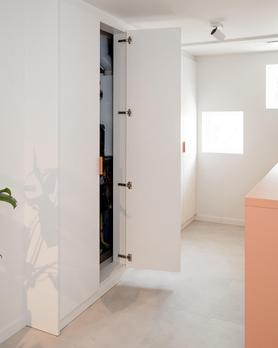 Customised technical cabinet in laundry room, cabinets in Front White with pink Tonton handles.