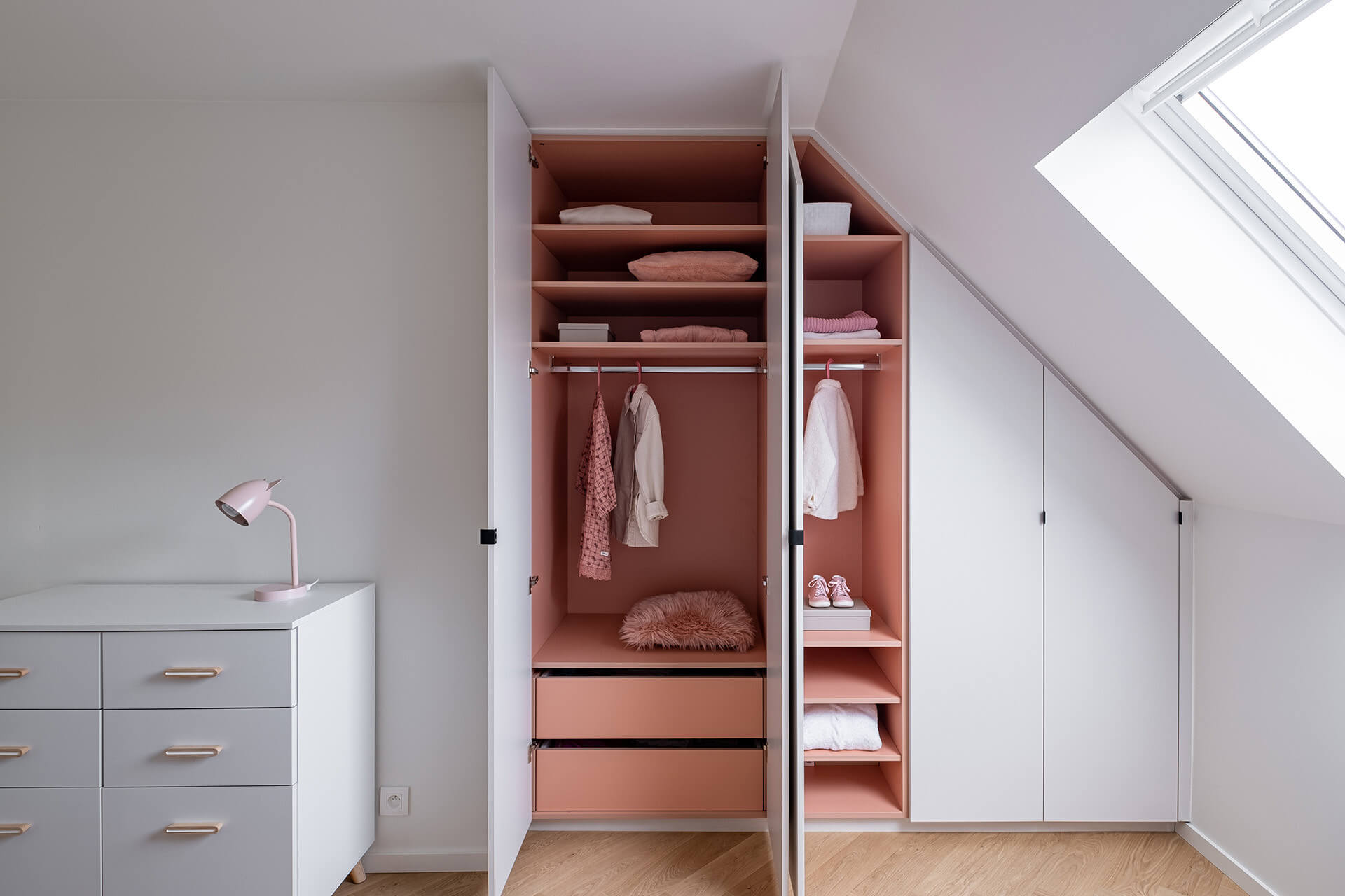 integrated closet under a sloping roof with a pink touch by maatkastenonline